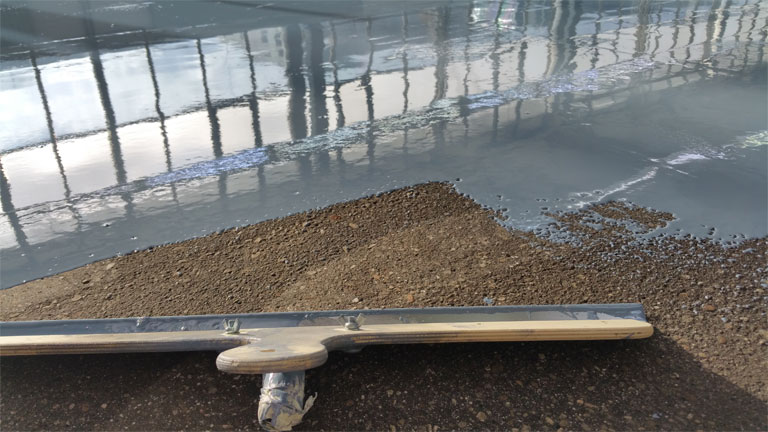 Beschichtung auf Estrich mit einer Rakel während den Arbeiten